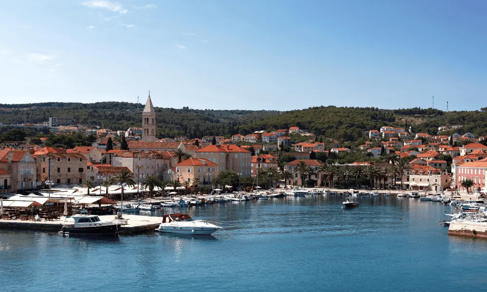 Vrboska, wyspa Hvar – nadmorska marina, kamienne domy i kultowa wieża kościelna otoczona wzgórzami porośniętymi sosnami