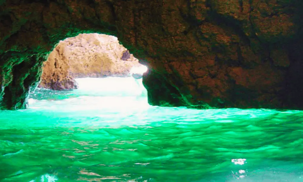 Wnętrze Zielonej Jaskini w pobliżu Visu, gdzie widać odbijające się szmaragdowe światło na wodzie i skalistych ścianach jaskini.