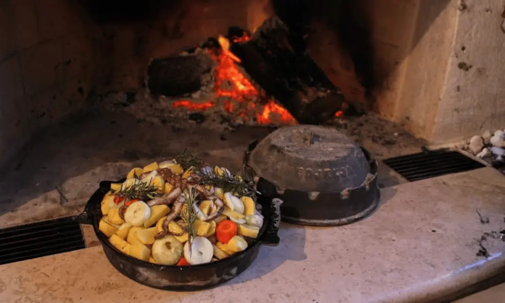 Tradycyjna peka z ośmiornicy pieczona pod żelaznym dzwonem w rustykalnej konobie w Hvarze z otwartym kominkiem.