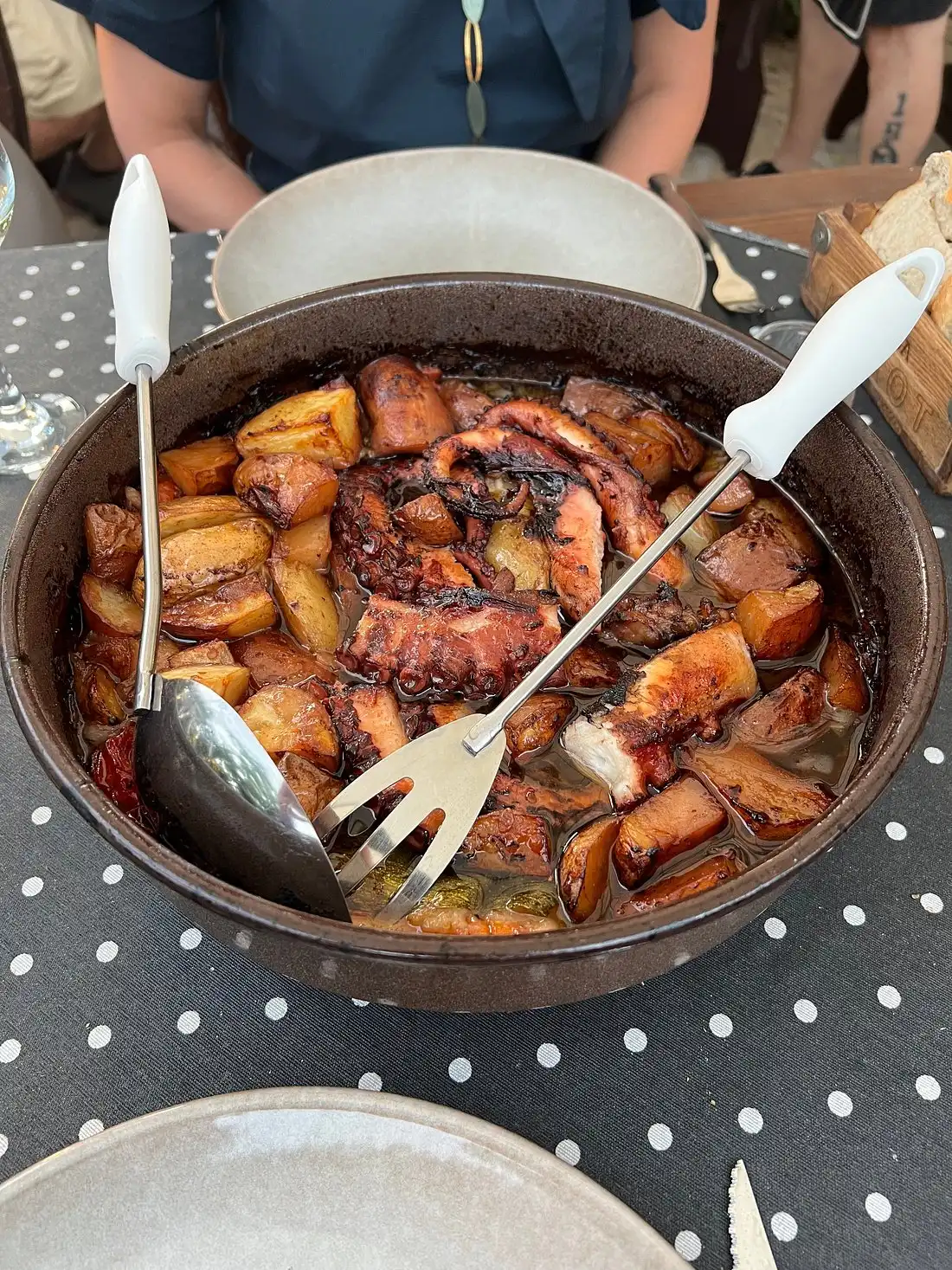 Traditional Croatian octopus ‘ispod peke’ served in a rustic pan with roasted potatoes, vegetables, and olive oil, ready to be shared at a konoba-style restaurant table