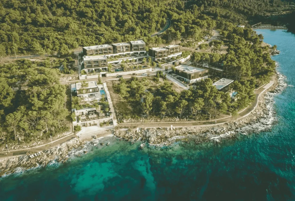 Aerial view of Maslina Resort on Hvar, nestled among dense pine forest along the rocky coastline, with turquoise sea surrounding the secluded luxury property
