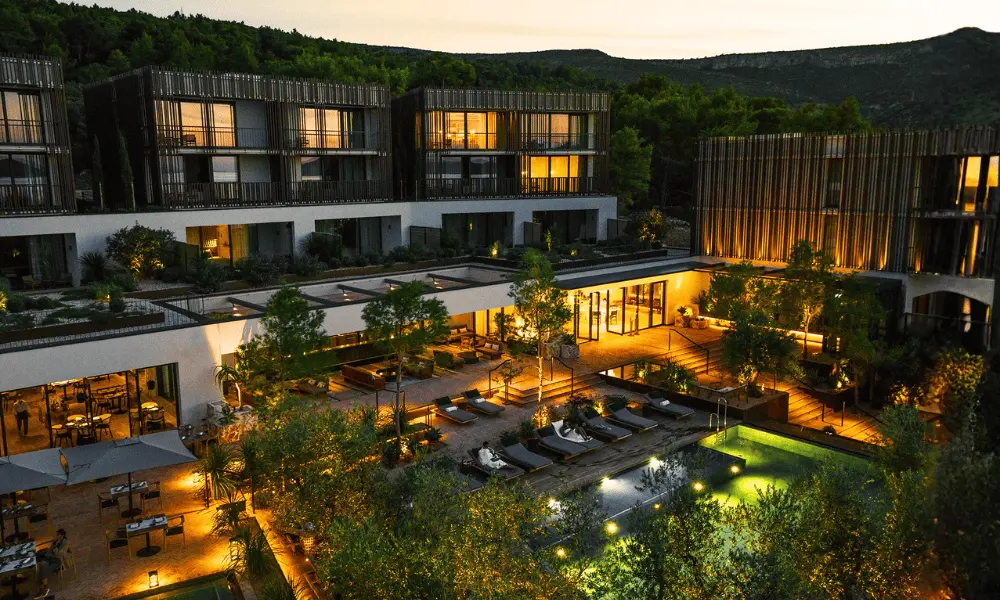 Wieczorny widok na Maslina Resort, luksusowy 5-gwiazdkowy hotel na wyspie Hvar, z ciepłym oświetleniem, nowoczesnymi apartamentami i zagospodarowanym terenem basenowym.