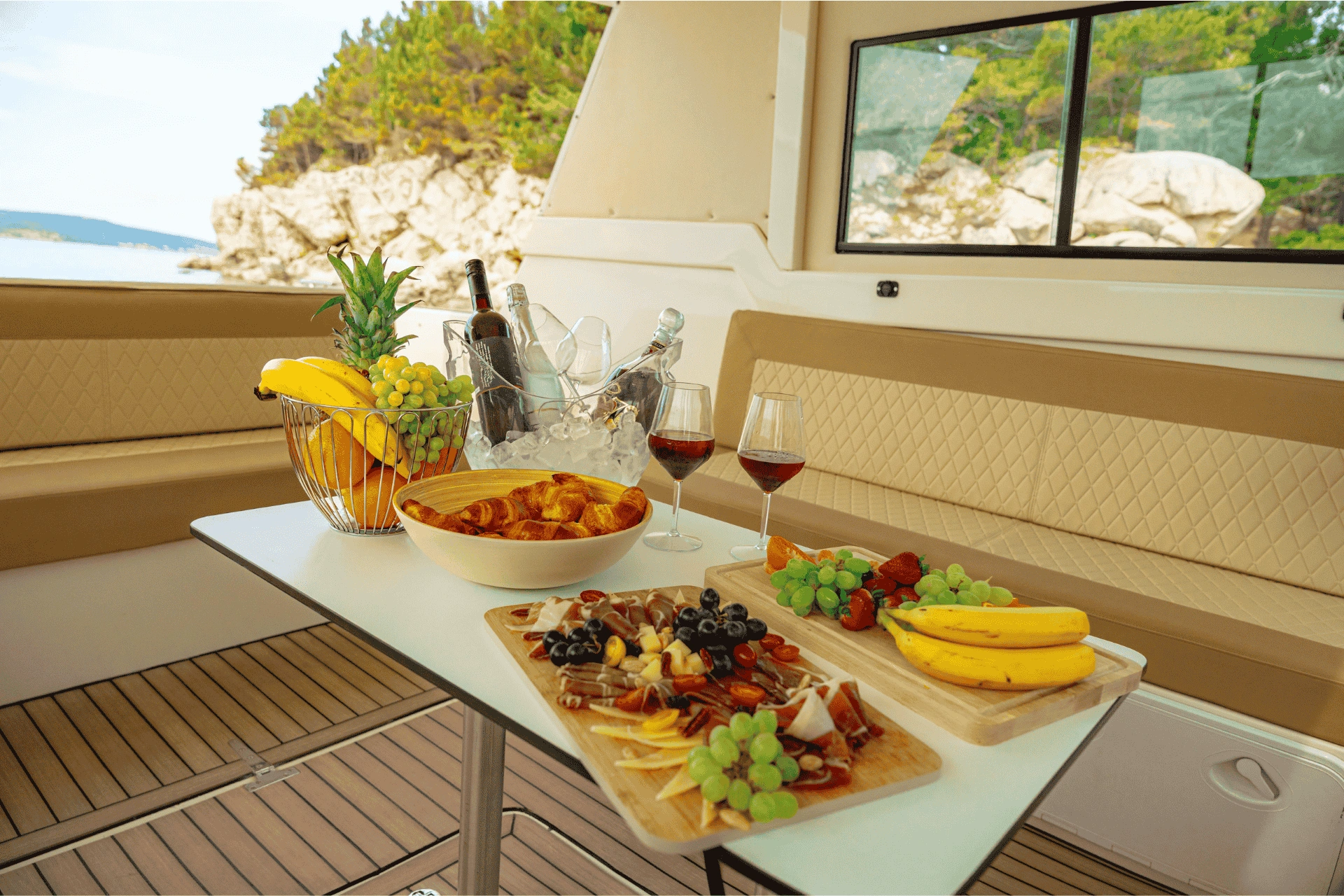 Fresh fruit, wine, and Mediterranean snacks arranged on a table inside a boat overlooking the coastline of Hvar