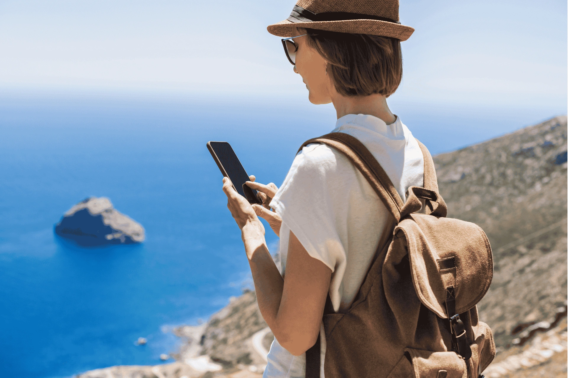 Traveler using a smartphone while overlooking the coastline and cliffs of Hvar